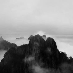 black and white photograph of mountains in the fog