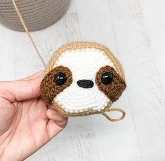 a hand holding a small crocheted stuffed slotty toy in it's mouth