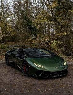 a green sports car parked in front of some trees