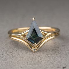 a gold ring with a green stone in the center and two diamonds on each side