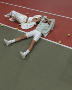 a man laying on the ground with tennis balls in front of him and another person lying down next to him