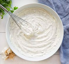 a bowl filled with white sauce next to some parsley