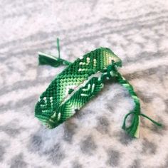 two green bracelets with white and black designs on them sitting on top of a bed