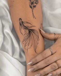 a woman's arm with a tattoo on it that has a goldfish and flowers