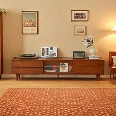 a living room with two chairs, a table and pictures on the wall above it