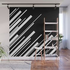 an abstract black and white wall mural in a living room with wooden floors, bookshelves