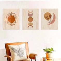 three wall hangings on the wall above a chair in a living room with a potted plant