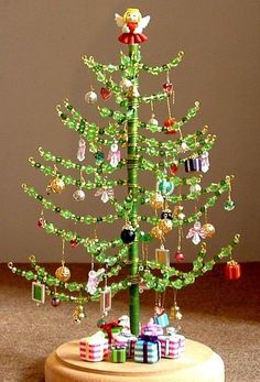 a green christmas tree with ornaments on it's base and presents under the top