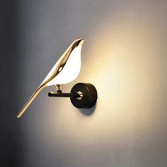 a wall light that has a bird on the back of it's arm and is lit up