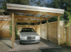 a car is parked in the driveway under a pergolated area with wooden fences