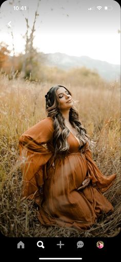 a woman in an orange dress is sitting in the middle of tall grass and looking up