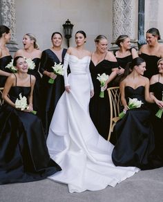 a group of women in black dresses standing next to each other with bouquets on their heads