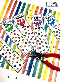 four bookmarks with scissors on top of them in front of a rainbow striped background