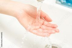 a person's hand under a running water faucet in a bathroom sink