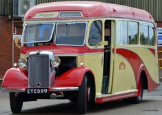 an old red and yellow bus parked in front of a brick building