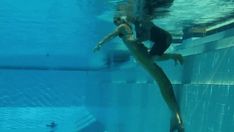 a woman is diving in the pool with her feet on the edge of the water