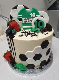 a soccer themed birthday cake with chocolate and strawberries on the bottom, along with a number 10 sign