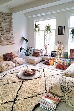 a living room filled with lots of furniture and pillows on top of a white rug