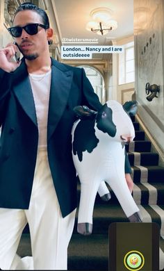 a man standing next to a fake cow in front of a staircase with the caption london - nanny and i are forbidden