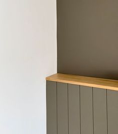 an empty room with a wooden shelf on the wall and a white wall behind it