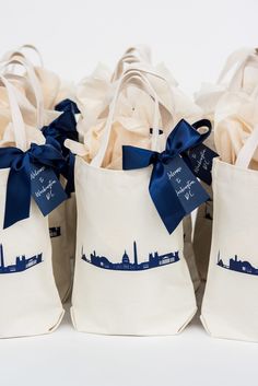 three white bags with blue ribbon tied around them and some buildings in the background,