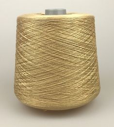 a spool of gold colored thread on a white background