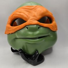 a turtle mask with an orange eye patch on it's face and nose, sitting in front of a white background