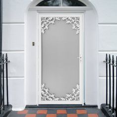 a white door with an ornate design on the side and black iron fence around it