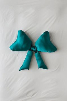 a pillow with a green bow on it sitting on top of a white bed sheet