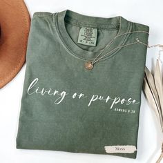 a t - shirt that says living on purpose is next to a hat