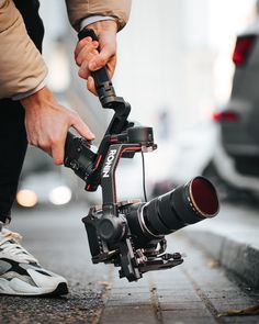 a person is holding a camera on a tripod with a lens attached to it