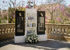 a white and black display with pictures on the front, flowers in vases at the back