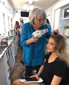 an older woman is getting her hair cut by a young lady in a blue shirt