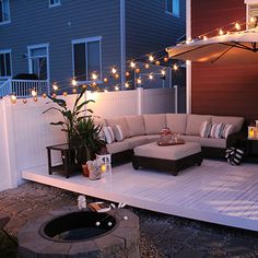 an outdoor living area with patio furniture and string lights on the side of the house