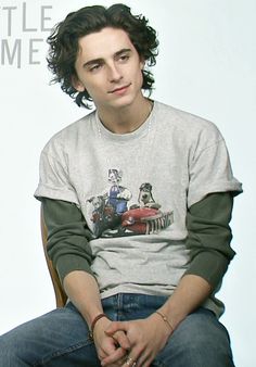 a young man sitting on top of a chair wearing a shirt with dogs on it