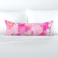 a white bed with pink and black pillows