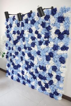 a blue and white crocheted wall hanging on the side of a building with three lights