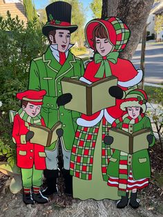 a group of people standing next to each other in front of a tree wearing green and red outfits