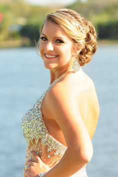 a woman in a wedding dress standing by the water with her hair in a braid