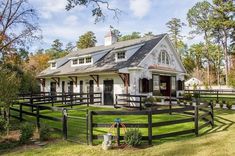 a white house with a black fence in front of it and trees around the yard