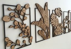 three metal wall art pieces with leaves and flowers on them, hanging on a white wall