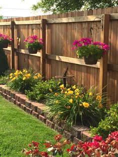 a wooden fence with flower pots on it and flowers growing in the planter boxes