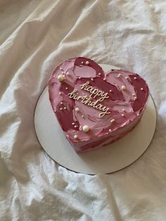 a heart shaped cake on a white plate with pink frosting and pearls around the edges