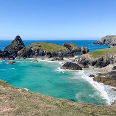 the ocean is blue and green with rocks on both sides that are surrounded by grass