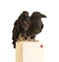 two black birds sitting on top of a wooden block