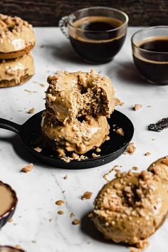 three donuts with peanut butter frosting are on a black plate