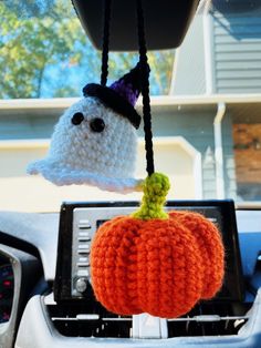 a knitted pumpkin hanging from a car dashboard