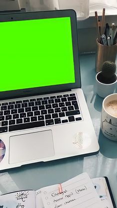 an open laptop computer sitting on top of a desk next to a cup of coffee