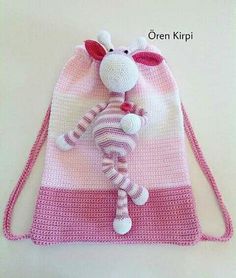 a pink and white crocheted bag with a stuffed animal on it's side