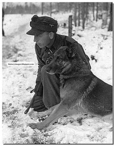 a man kneeling down next to a dog in the snow